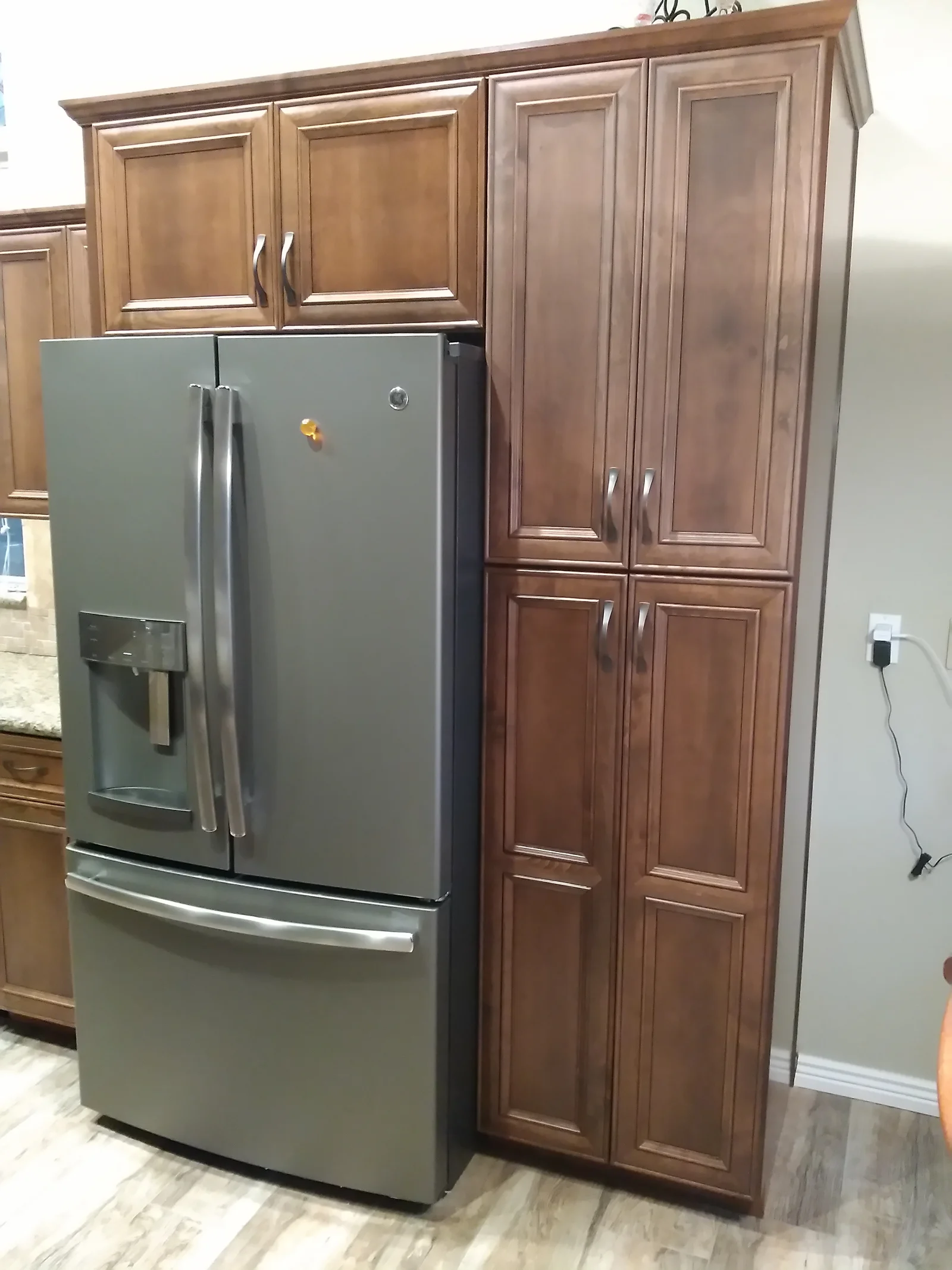 Cherry wood kitchen cabinets with stainless steel refrigerator and matching pantry tower