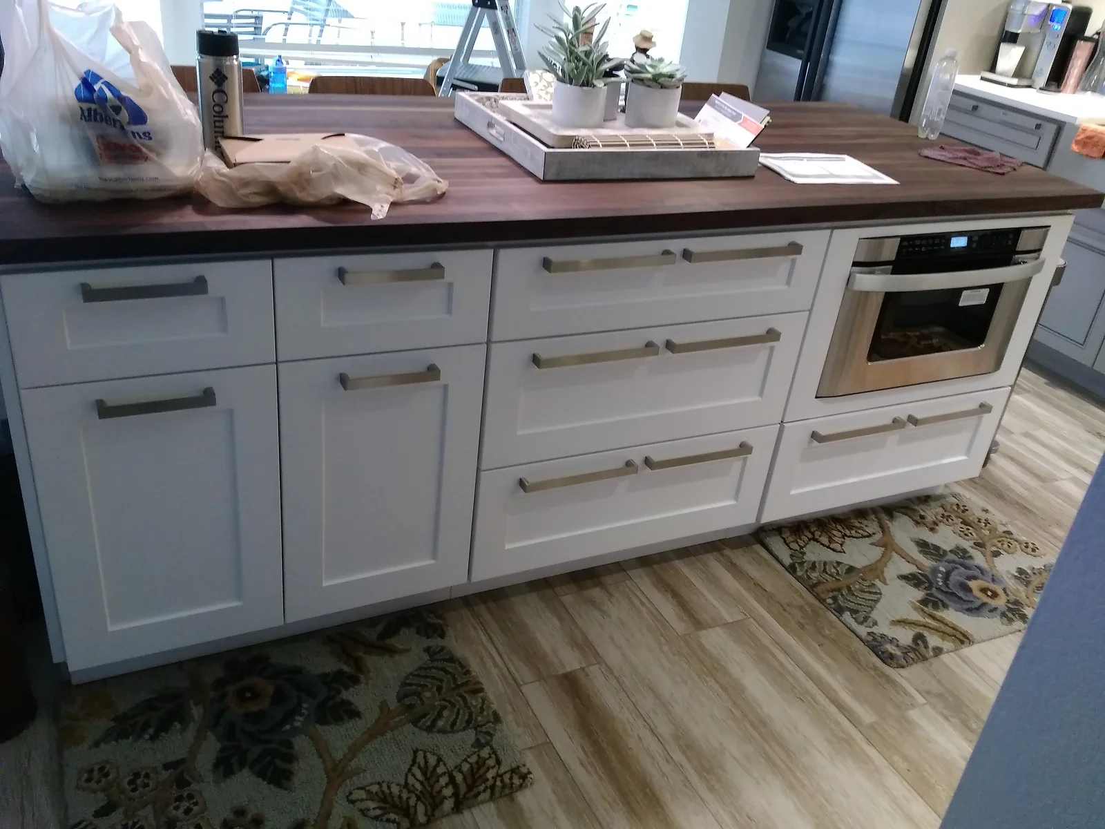 White shaker cabinetry with dark wood countertop, stainless steel oven, and brushed nickel hardware