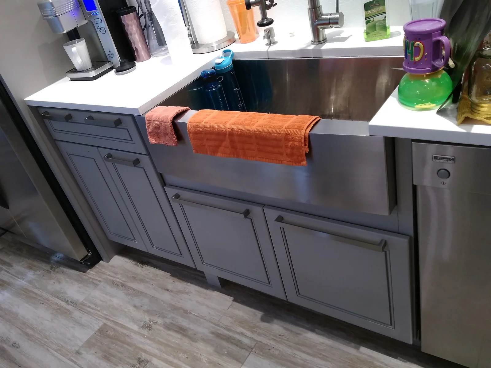 Gray kitchen cabinets with farmhouse sink, white quartz countertops, stainless steel appliances