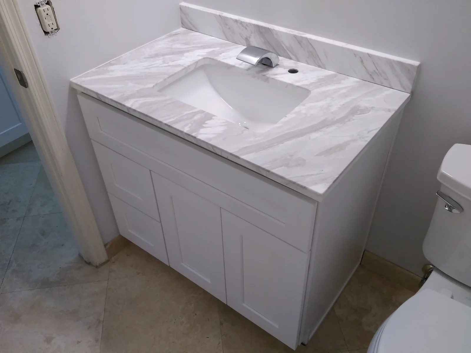 White marble countertop with integrated sink on white vanity cabinet with chrome faucet
