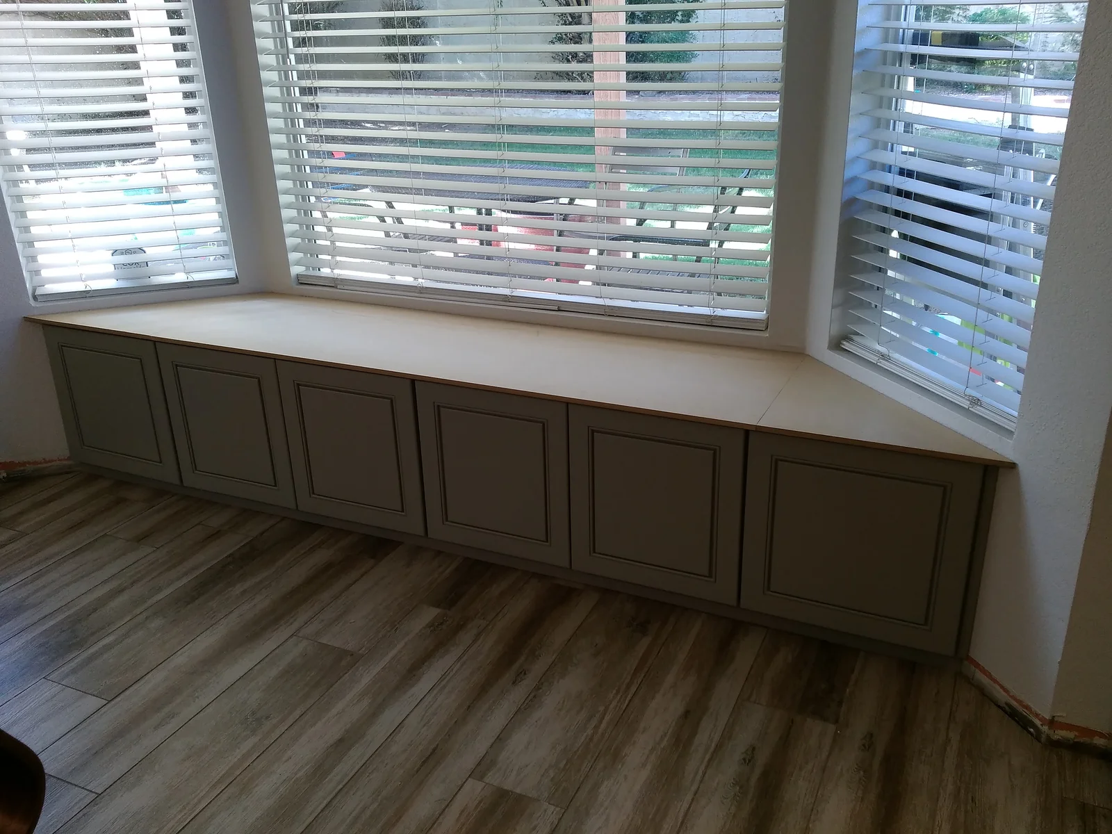Custom built-in window seat with six-panel cabinet doors and cushioned top beneath three windows