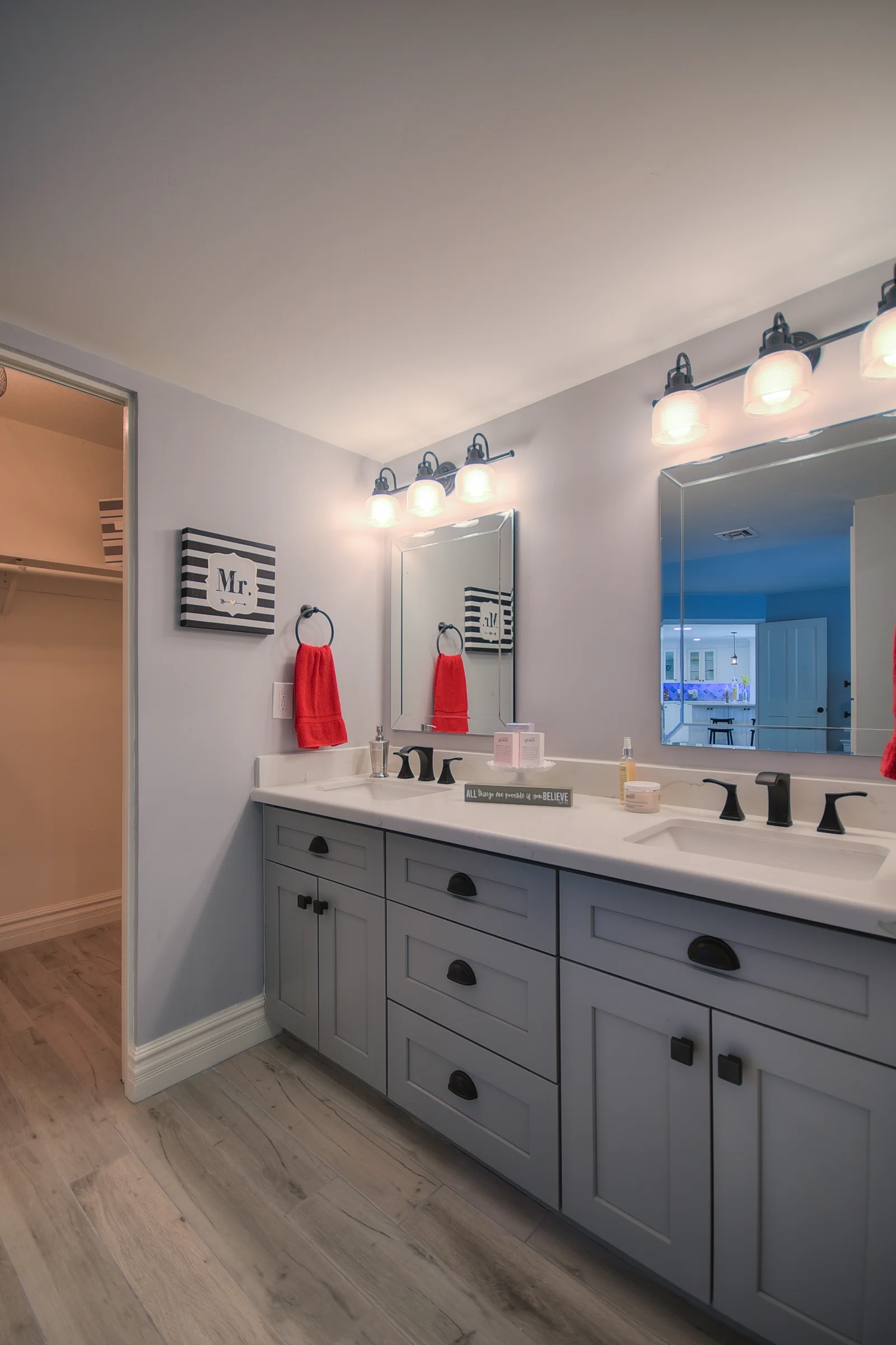 Gray cabinetry vanity with white quartz countertop, dual sinks, framed mirrors, and black vanity lighting