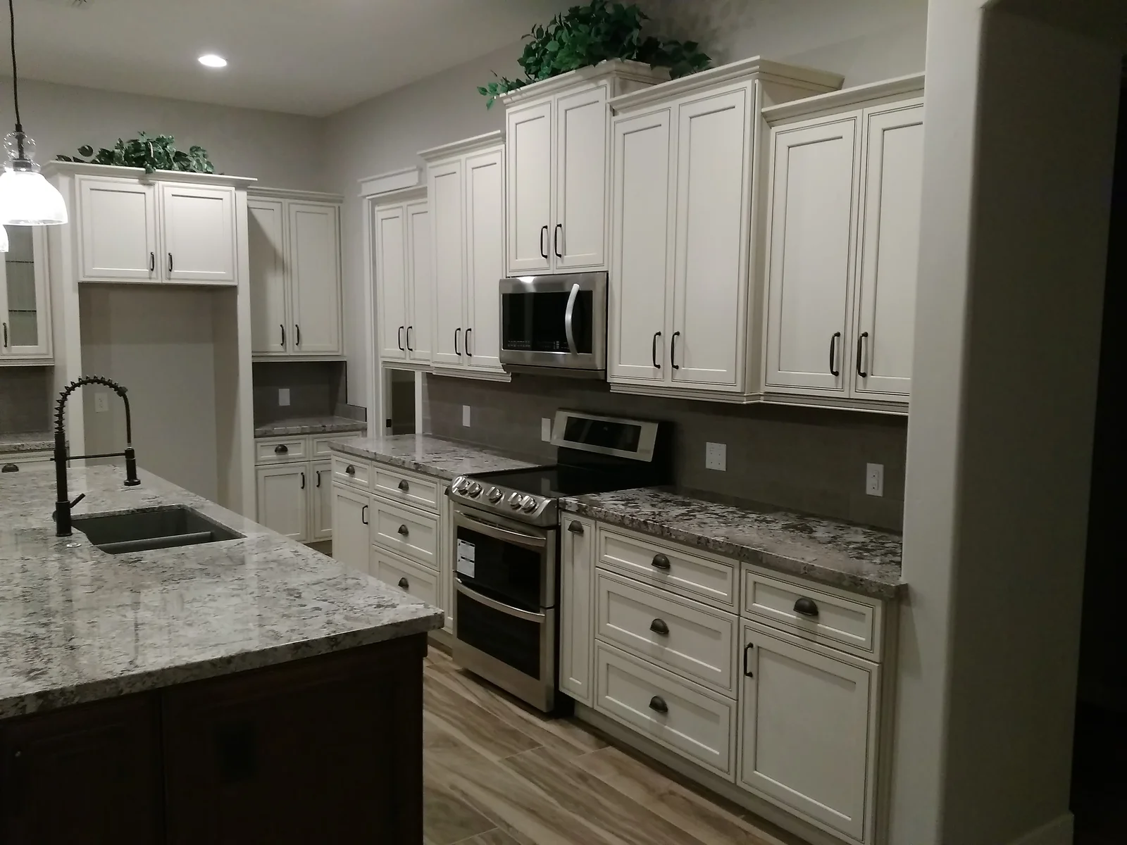 White kitchen cabinets, granite countertops, stainless steel appliances, island with waterfall edge