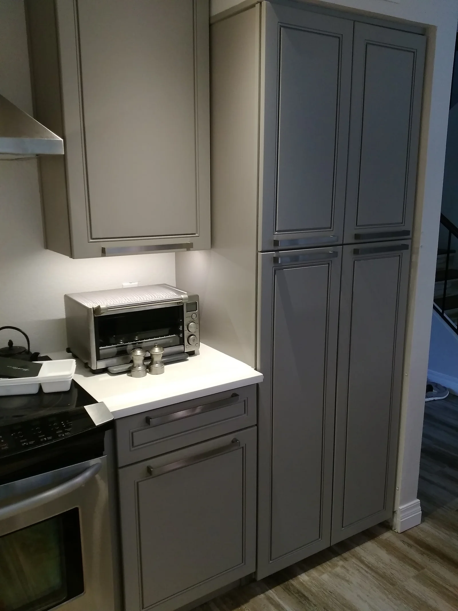 Gray shaker cabinets with white quartz counters and under-cabinet lighting in modern kitchen