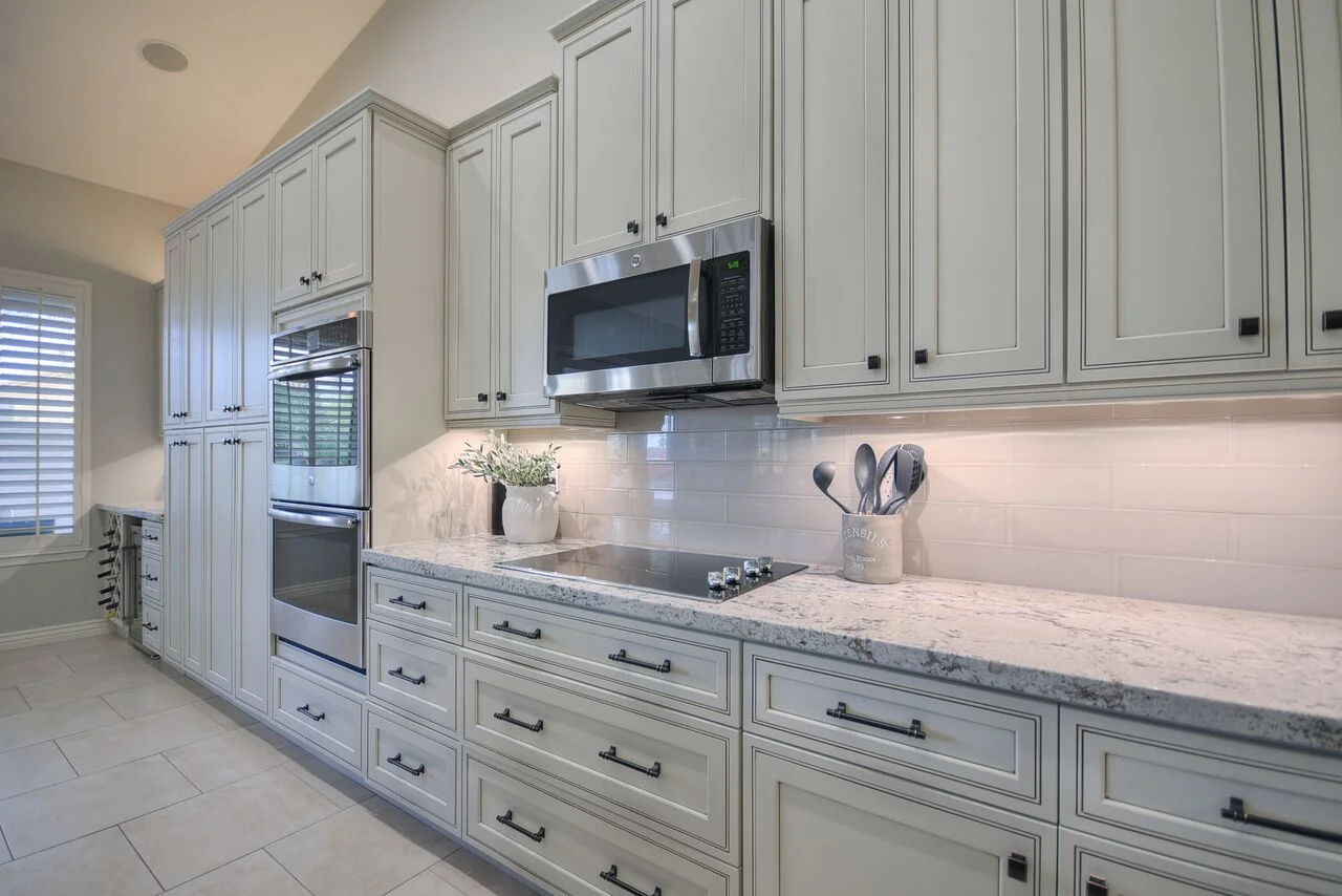 Light gray shaker cabinets, marble countertops, white subway tile backsplash, stainless steel appliances