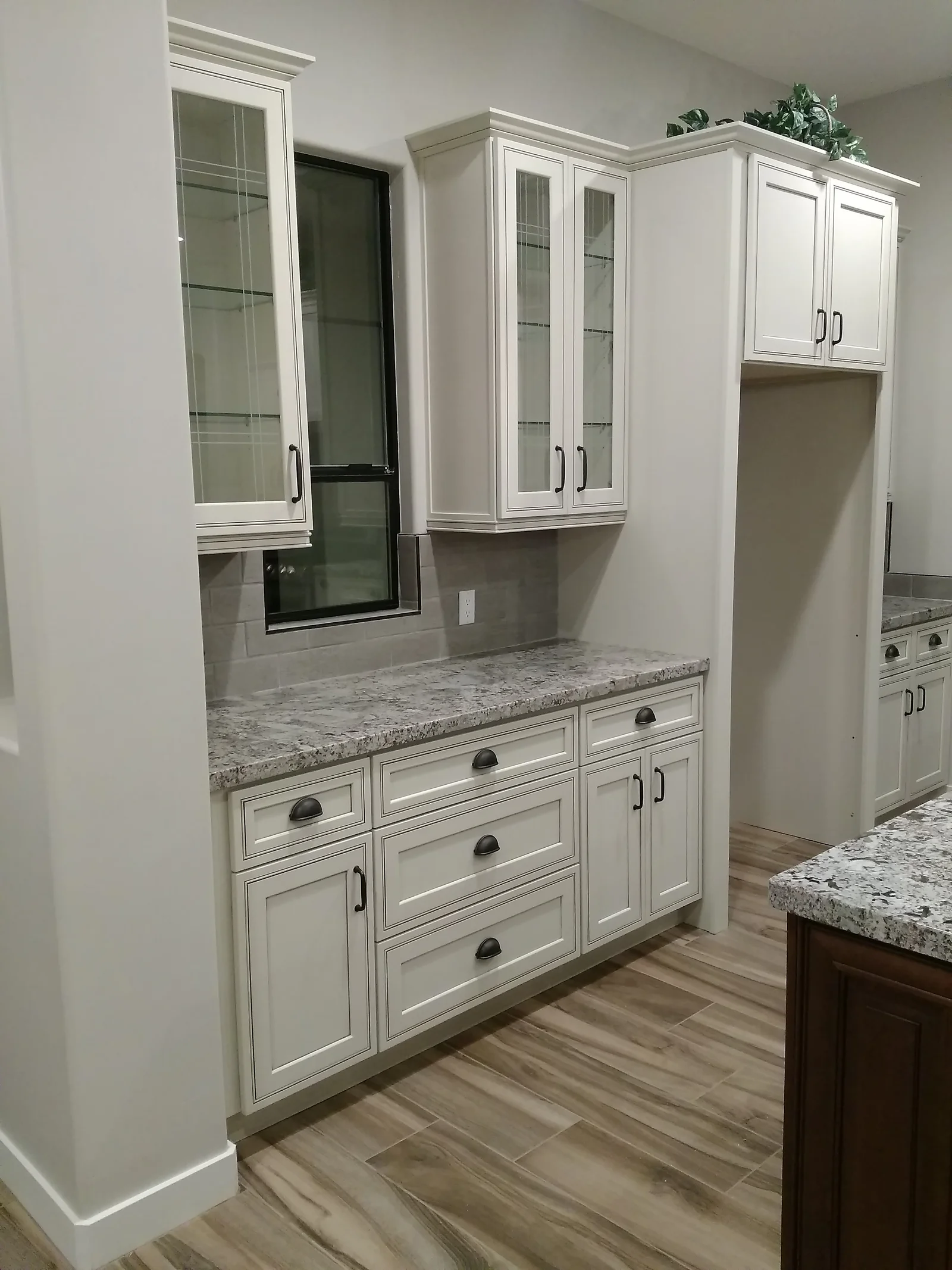 White shaker cabinets with granite countertops, glass-front uppers, and wood plank flooring