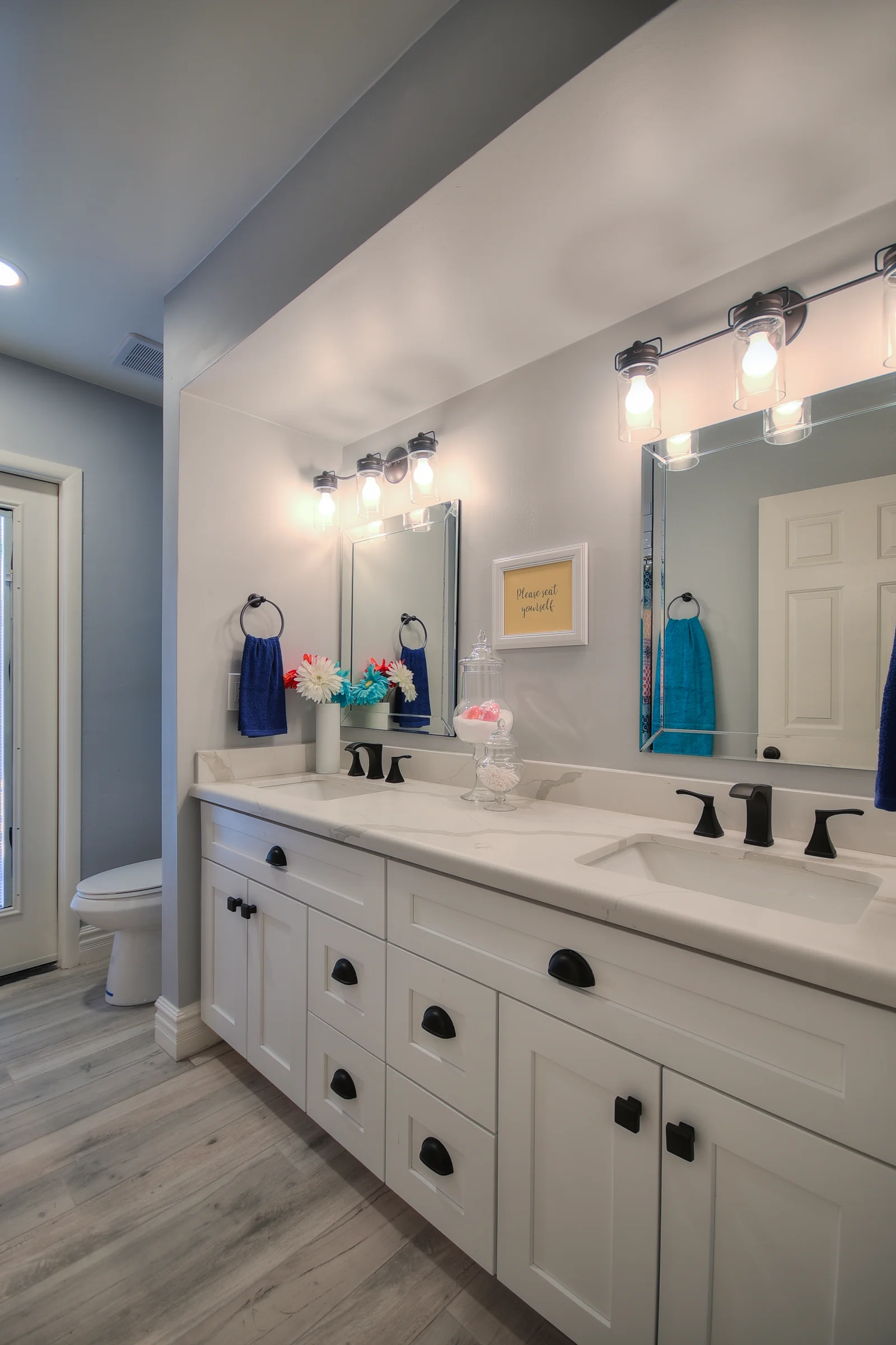 Dual-sink white vanity with quartz countertop, framed mirrors, and contemporary lighting fixtures